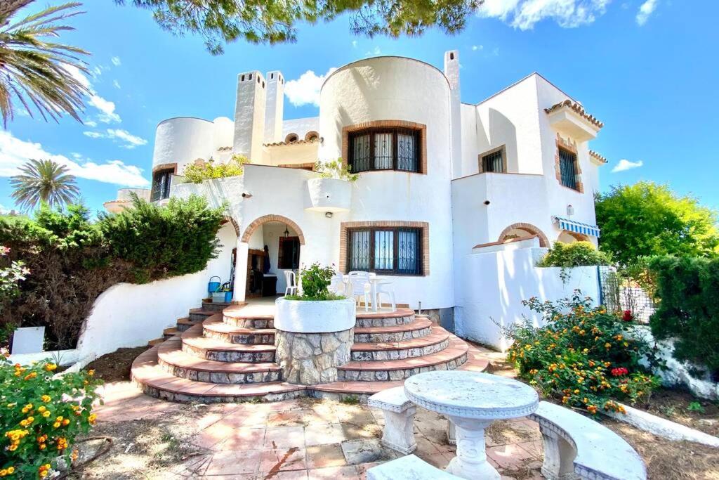 Casa blanca grande con escaleras y mesa en Casa de Mont-roig delante de la playa en Montroig