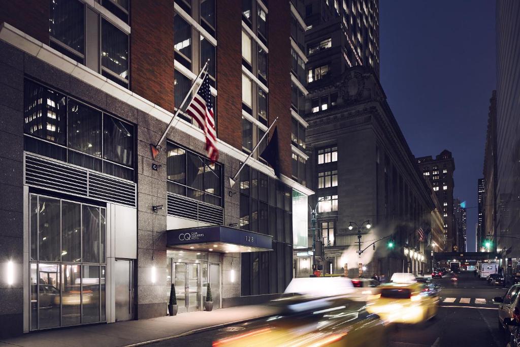 a city street at night with cars driving past a building at Club Quarters Hotel Grand Central, New York in New York