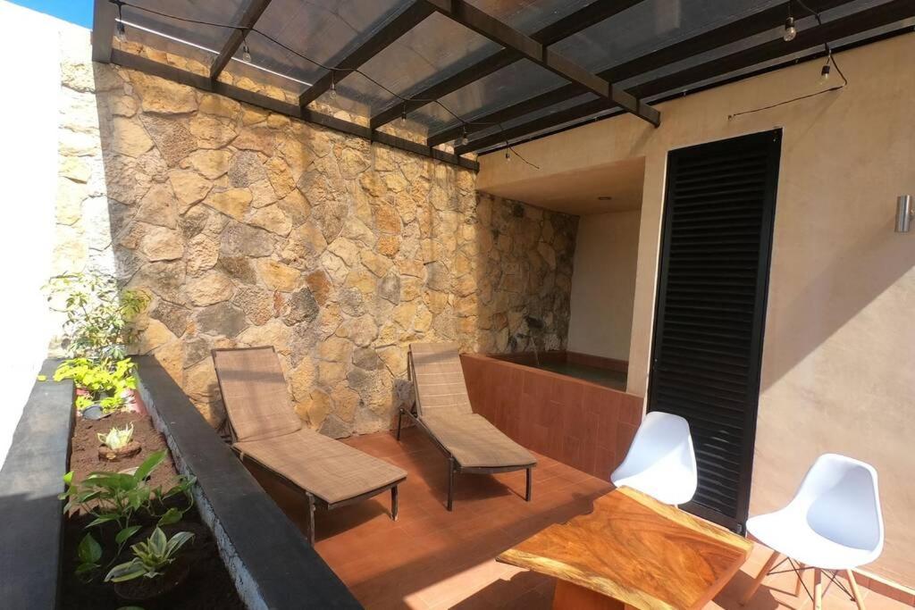 een patio met 2 stoelen en een stenen muur bij Casa Verano - 2 Hab 4 Baños Jacuzzi Rooftop A/C in Mérida