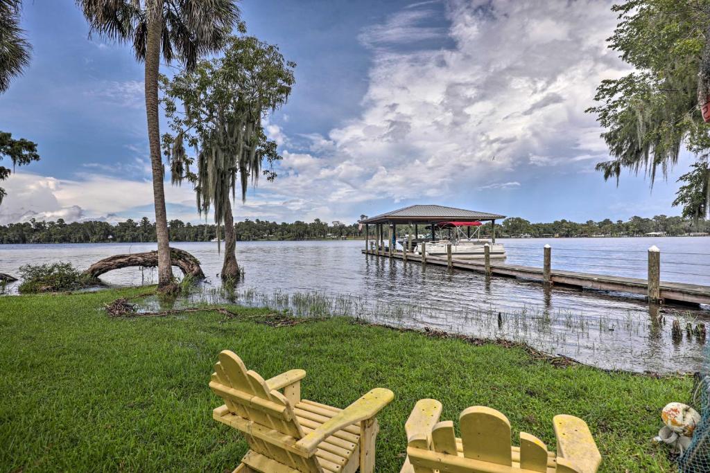 a group of chairs sitting on the grass next to a dock at Island Escape with Slip and Lift - Boat Access Only! in Georgetown