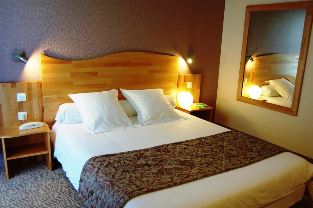 a hotel room with a large bed and a mirror at Hôtel Cositel, Coutances in Coutances