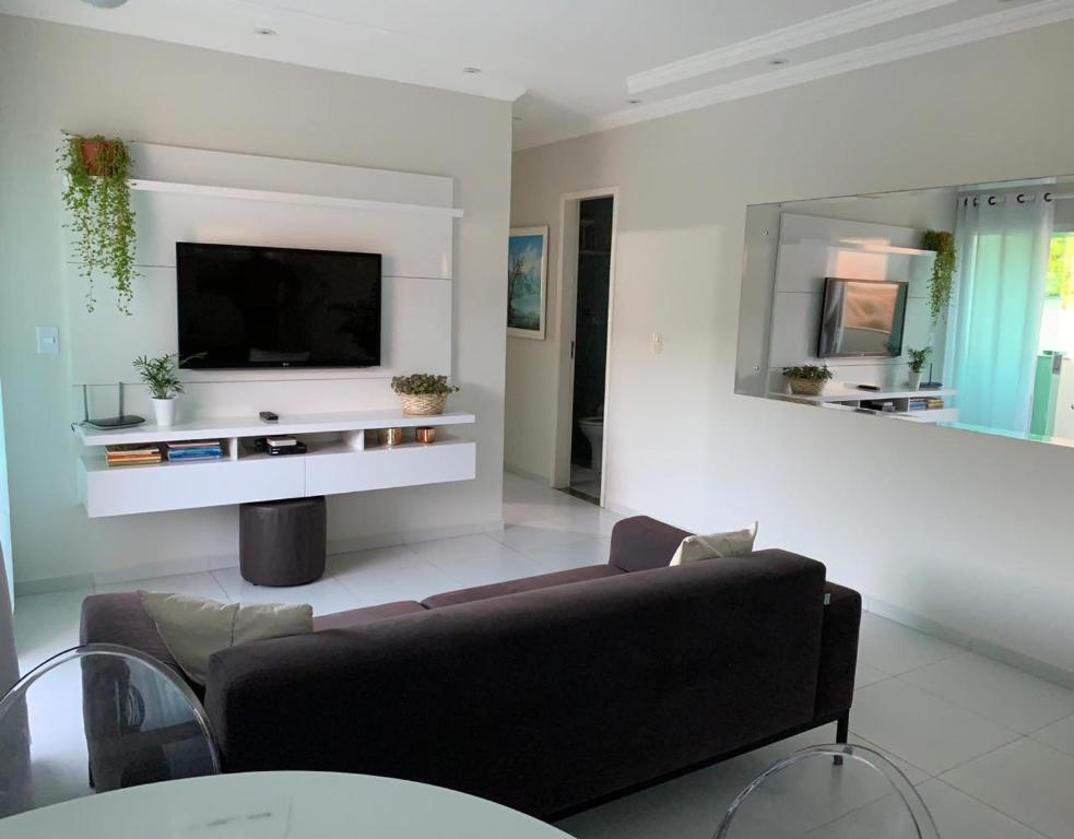 uma sala de estar com um sofá e uma televisão de ecrã plano em Excelente Apartamento Vista Mar em Maragogi em Maragogi