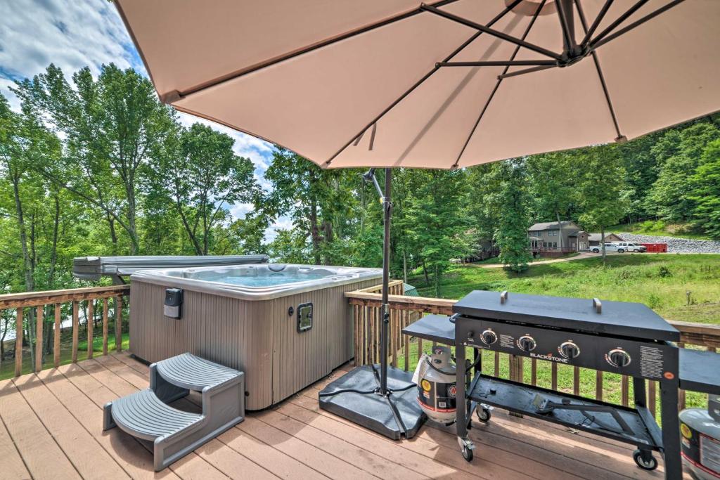 KuttawaLakefront Rest-Ashored Home with Private Dock!的甲板上配有热水浴池和烧烤架,甲板上配有遮阳伞