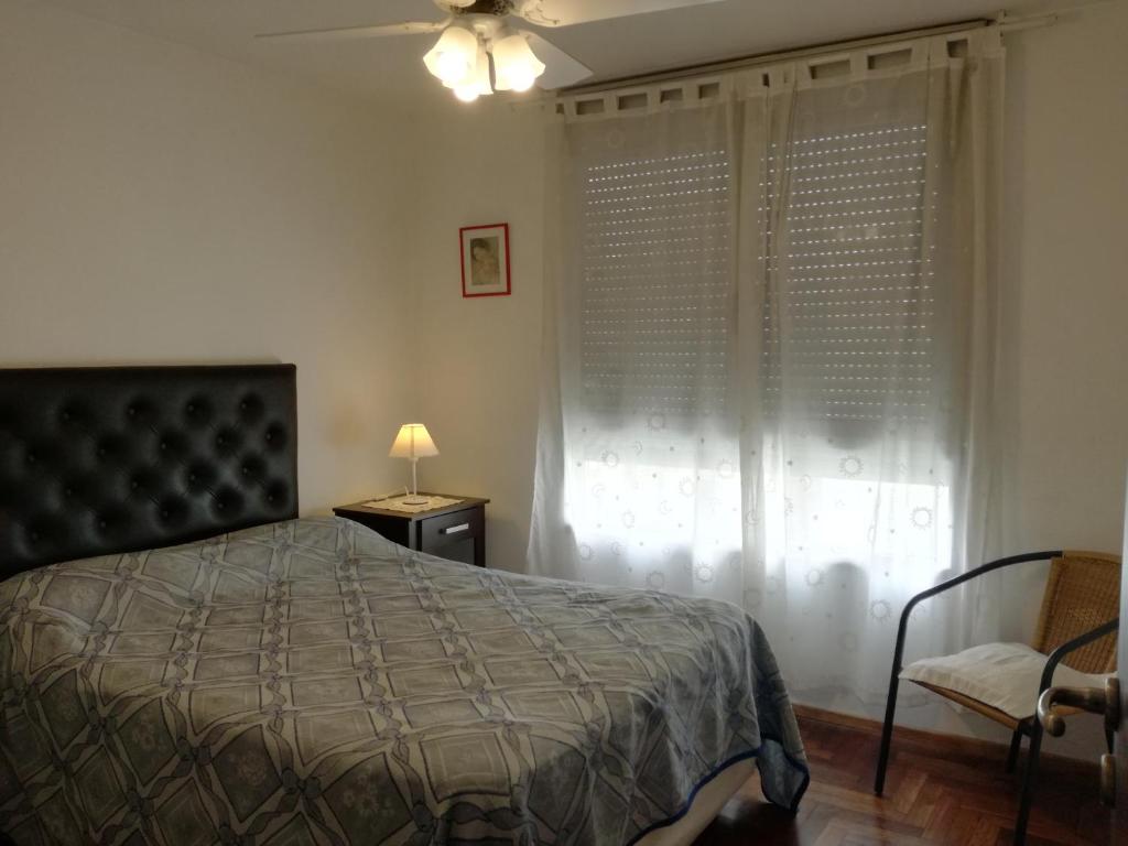 a bedroom with a bed and a chair and a window at Departamentos Córdoba Vaes in Cordoba