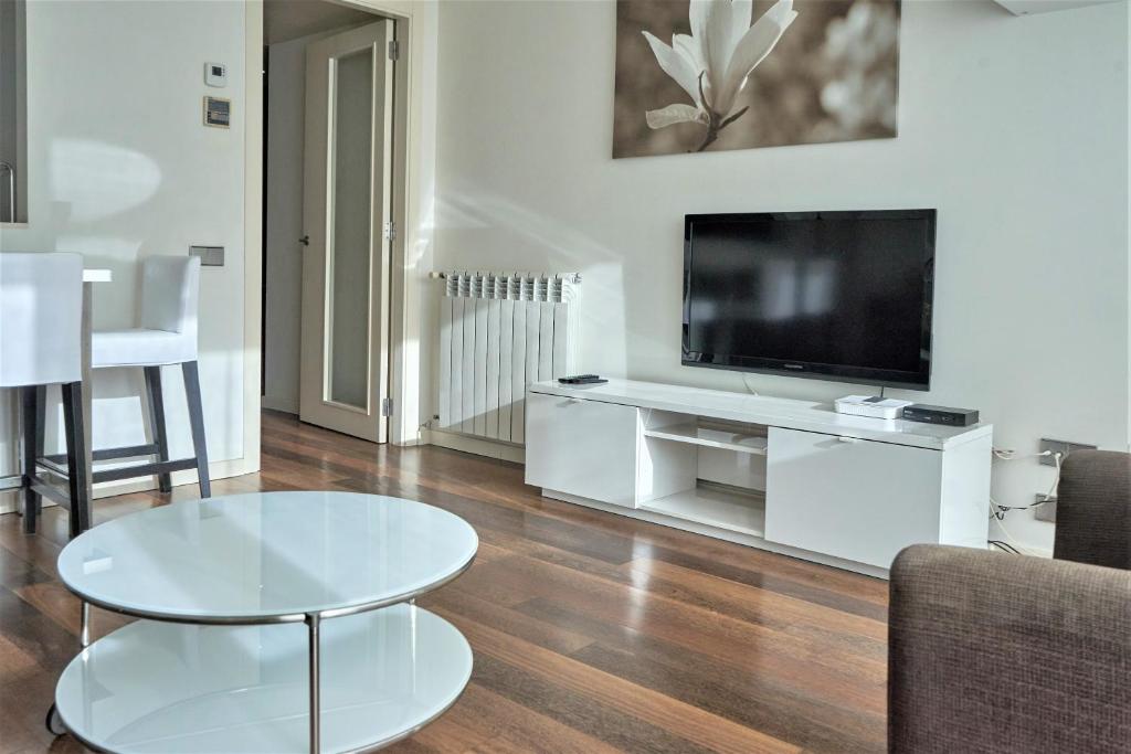 ein Wohnzimmer mit einem TV und einem Tisch in der Unterkunft Apartamento Via Augusta 153 in Barcelona