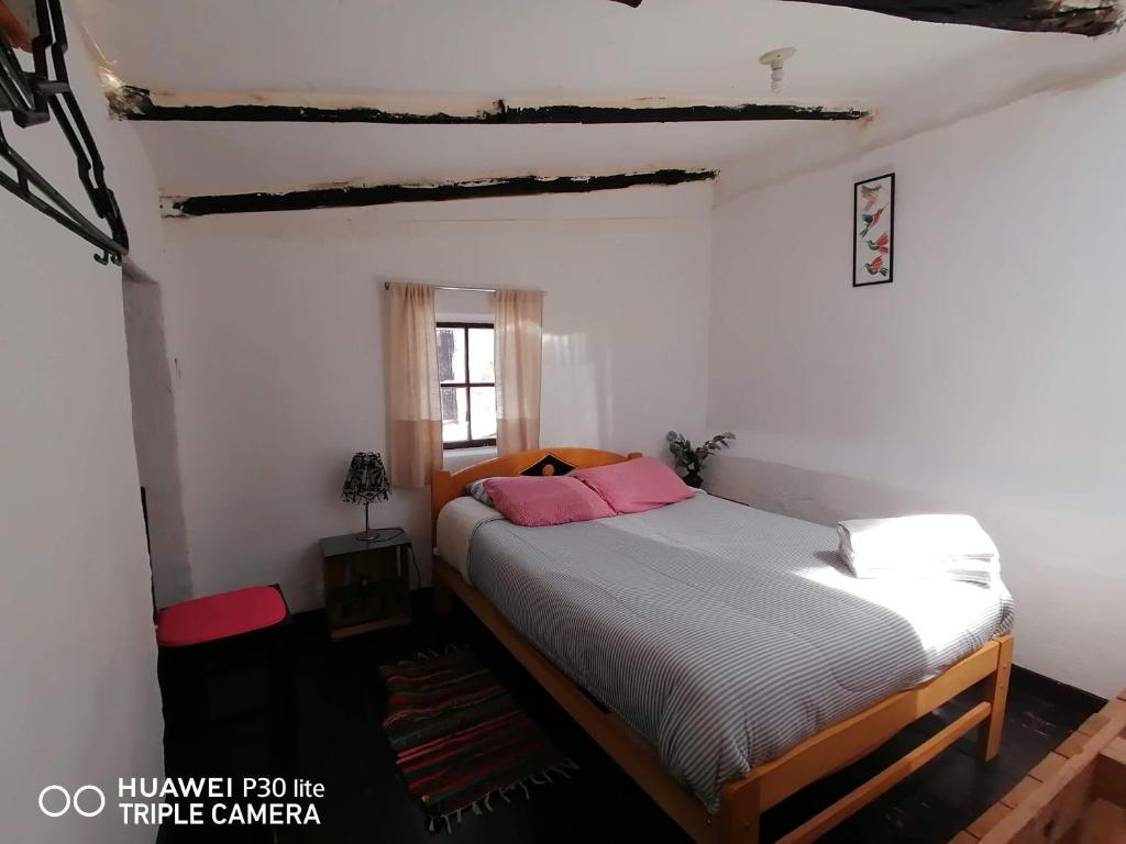 ein Schlafzimmer mit einem Bett mit rosa Kissen darauf in der Unterkunft Asiriq Wasi Casita de huéspedes in Cusco