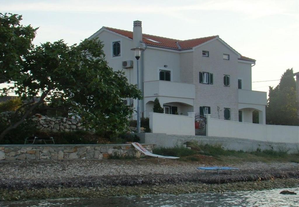 ein großes weißes Haus neben einem Wasserkörper in der Unterkunft Apartments Azur - 10 m from sea in Ilovik