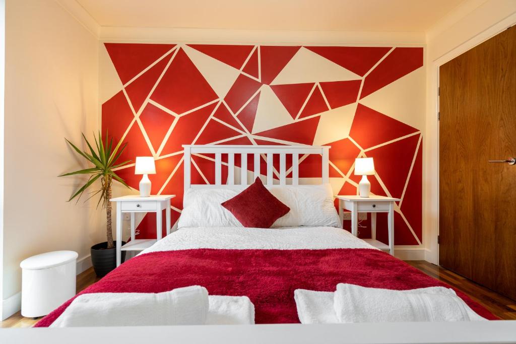 a bedroom with a bed with a red and white wall at Avril Serviced Apartment in Birmingham