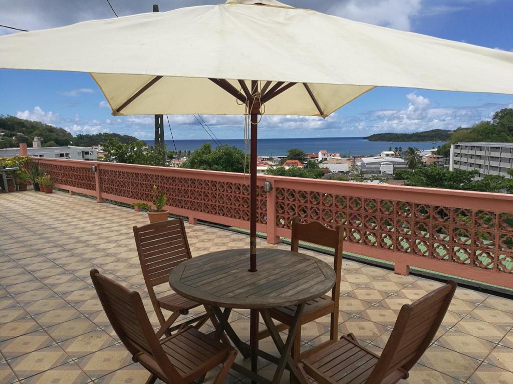 d'une table, de chaises et d'un parasol sur le balcon. dans l'établissement Villa la colliniere, à La Trinité