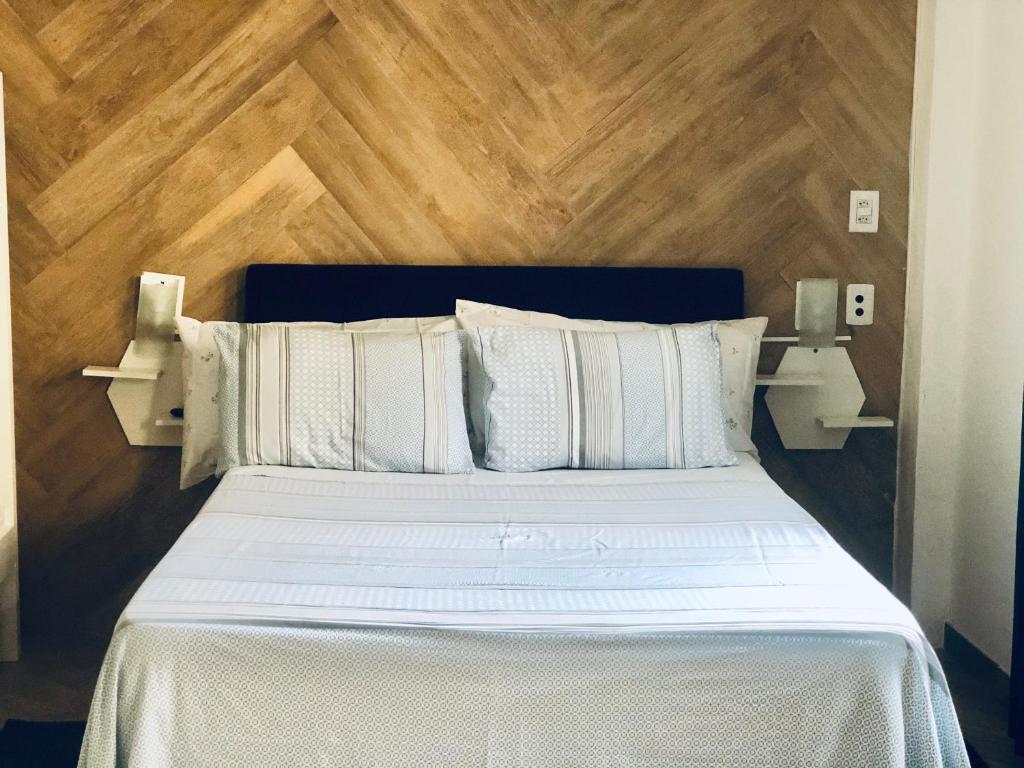 um quarto com uma cama branca e uma parede de madeira em Prado Guest House 2 em Florianópolis