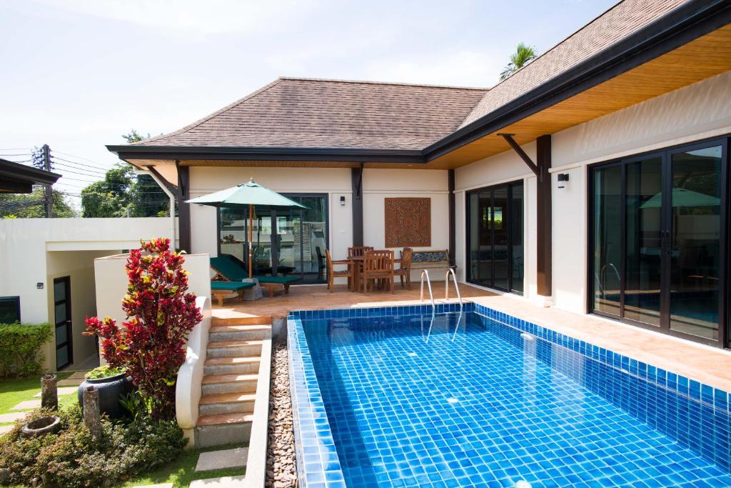 a swimming pool in the backyard of a house at Foxtail Palm Villa in Rawai Beach
