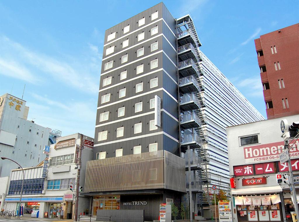 a tall building on a city street with buildings at Hotel Trend Kyobashi Ekimae in Osaka