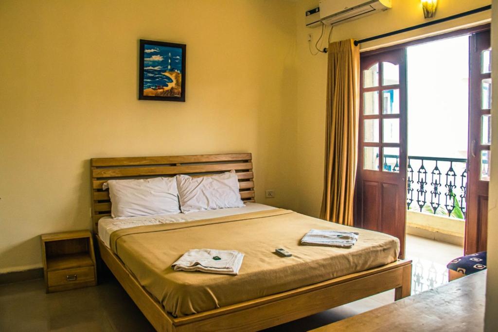 - une chambre avec un lit et une porte donnant sur un balcon dans l'établissement Utopia Holiday Candolim, à Candolim
