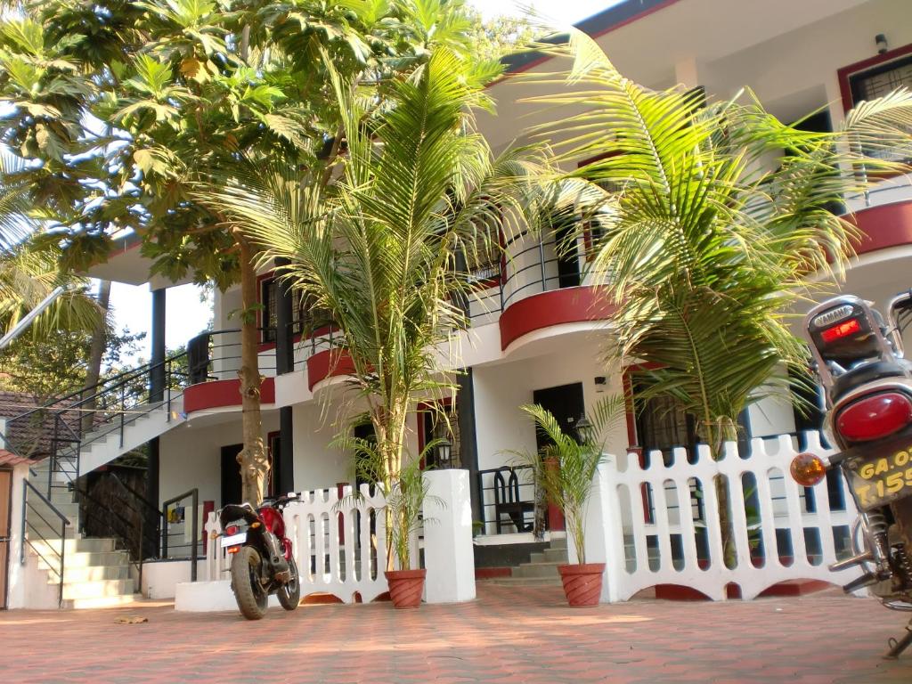 una motocicleta estacionada frente a un edificio con palmeras en Henmil Anjuna, en Anjuna