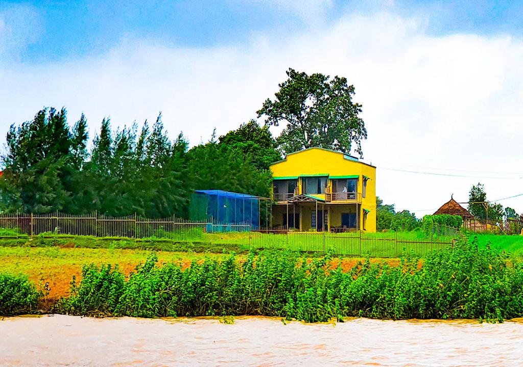 a yellow house sitting on top of a field at The Satpura Panchtatva Villa in Khāpa