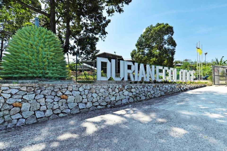 a stone wall in front of a building with a sign at Durian Ecolodge in Tampin