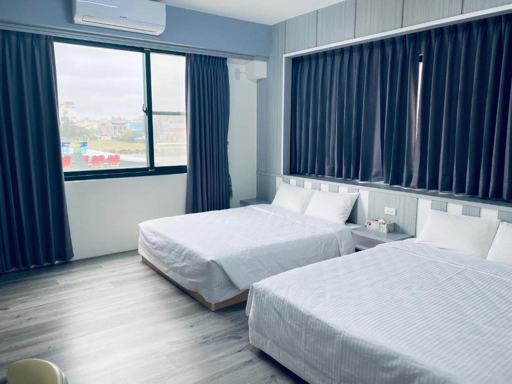 a hotel room with two beds and a window at Han Xiang Ju in Magong