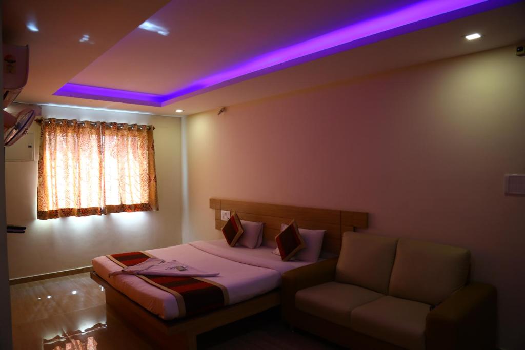 a bed and a couch in a room with purple lights at hotel fortune city in Bangalore