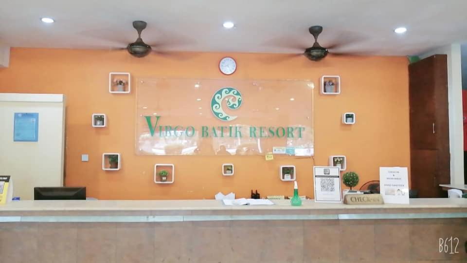 a lobby with a large orange wall with a clock at Virgo Batik Resort in Lumut