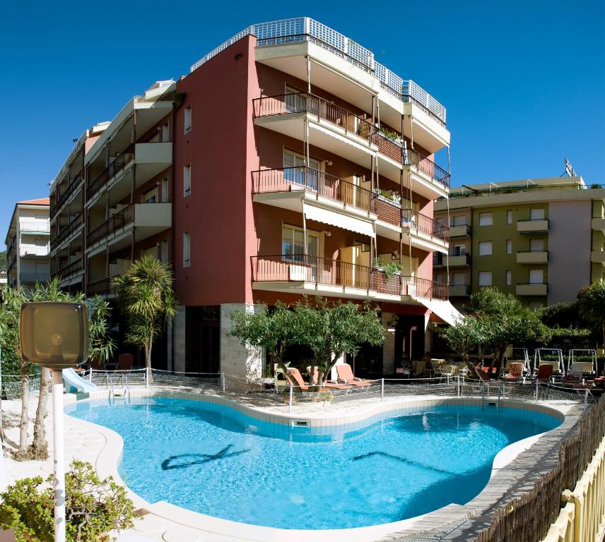 un hotel con piscina frente a un edificio en Ligure Residence en Pietra Ligure