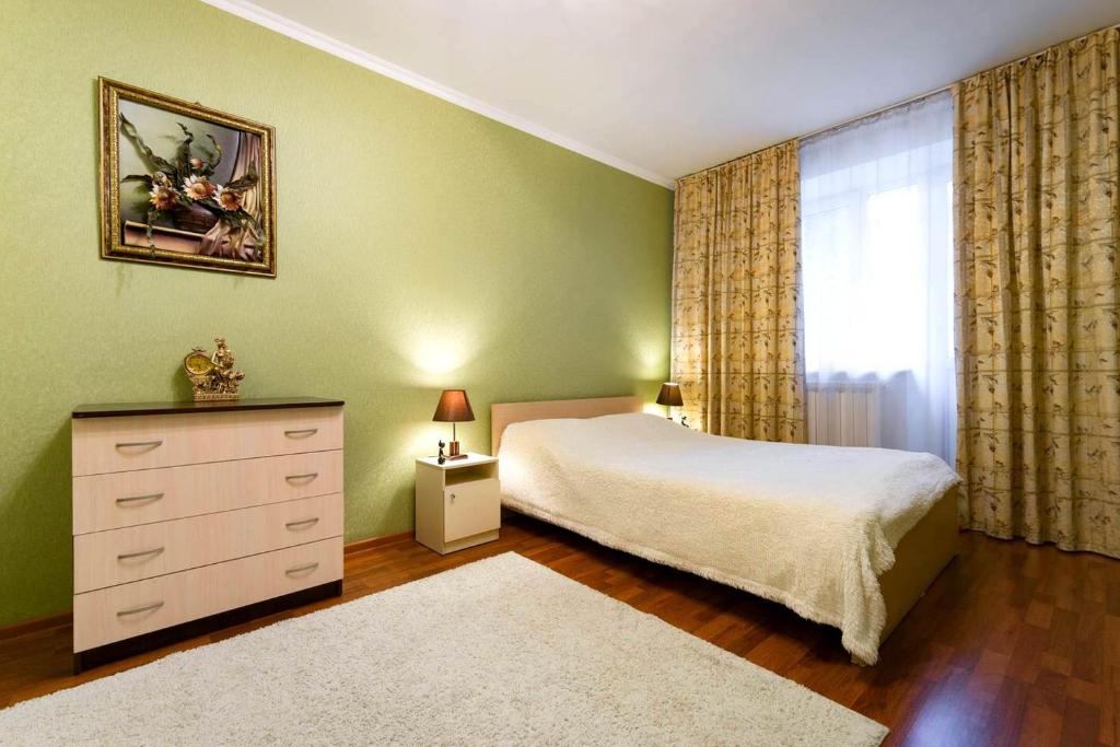 a bedroom with a bed and a dresser and a window at Nadezhda Apartments on Gogolya 117 in Almaty