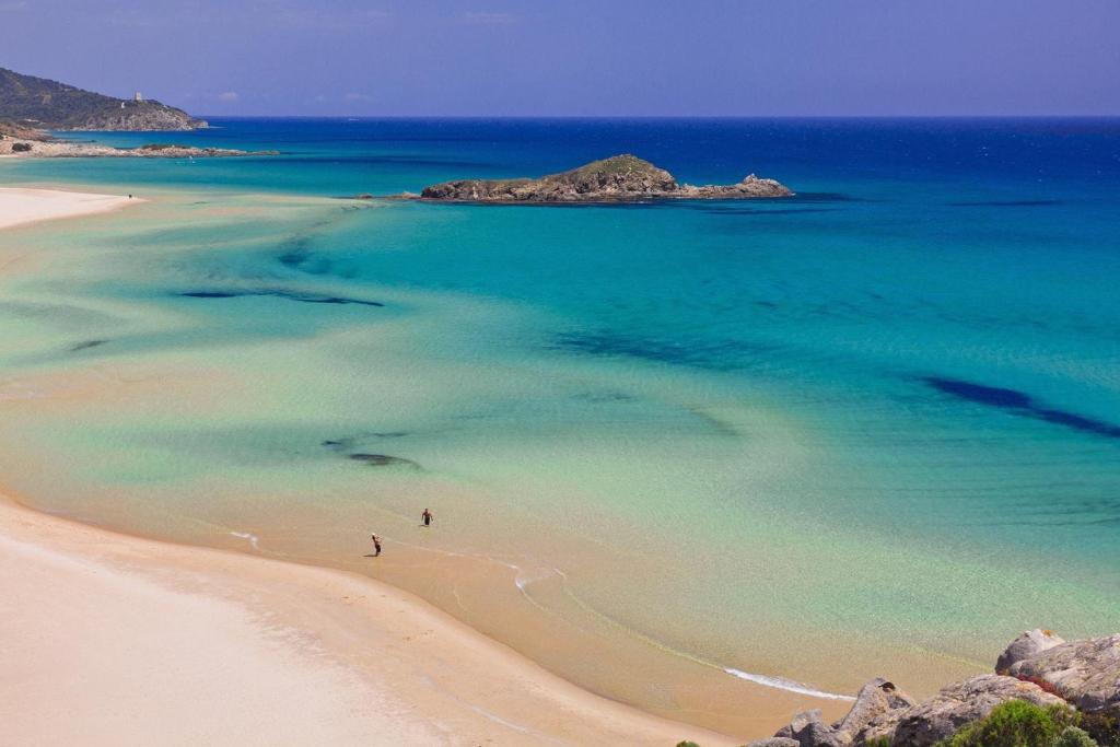 una persona caminando en una playa cerca del agua en Chia Zeffiro, en Chia