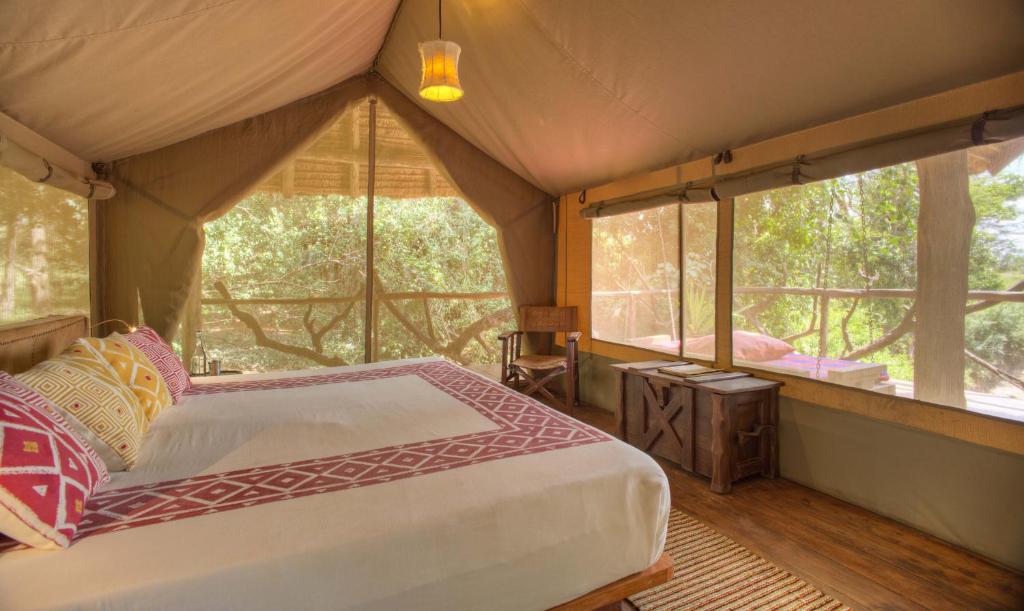 ein Schlafzimmer mit einem Bett in einem Zelt mit Fenstern in der Unterkunft Basecamp Masai Mara in Talek