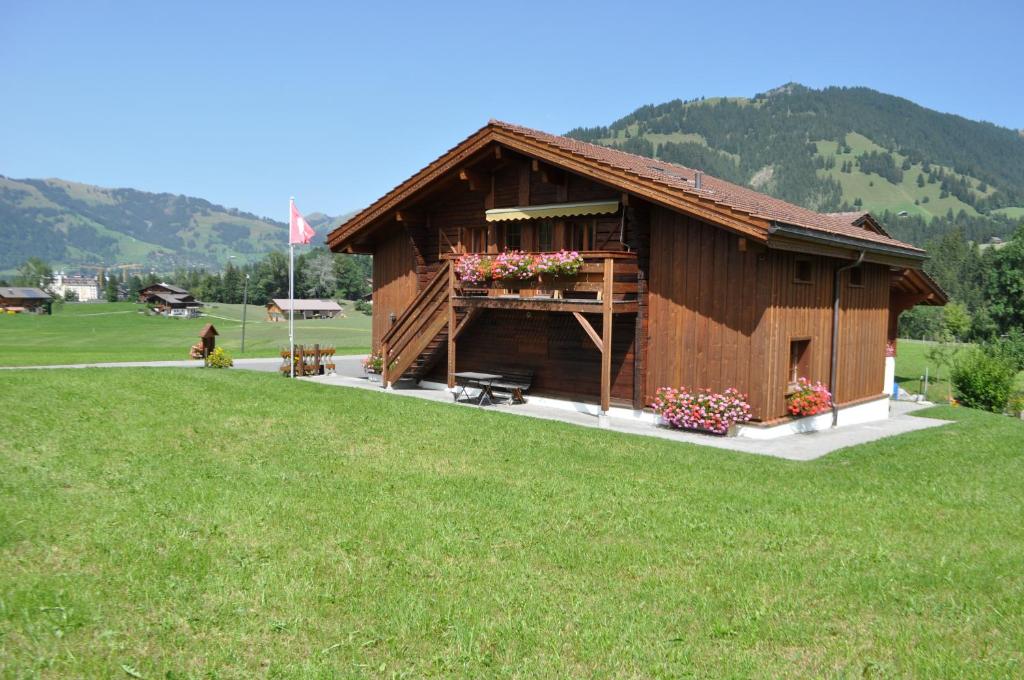 un pequeño edificio de madera con flores en un campo en Alpenchalet Weidhaus Gstaad Ferienwohnung im Dachstock, Studio und Zimmer im EG, en Gstaad