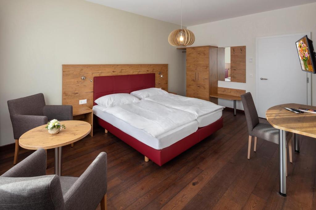 a bedroom with a bed and two tables and chairs at Hotel Roggen in Erschmatt