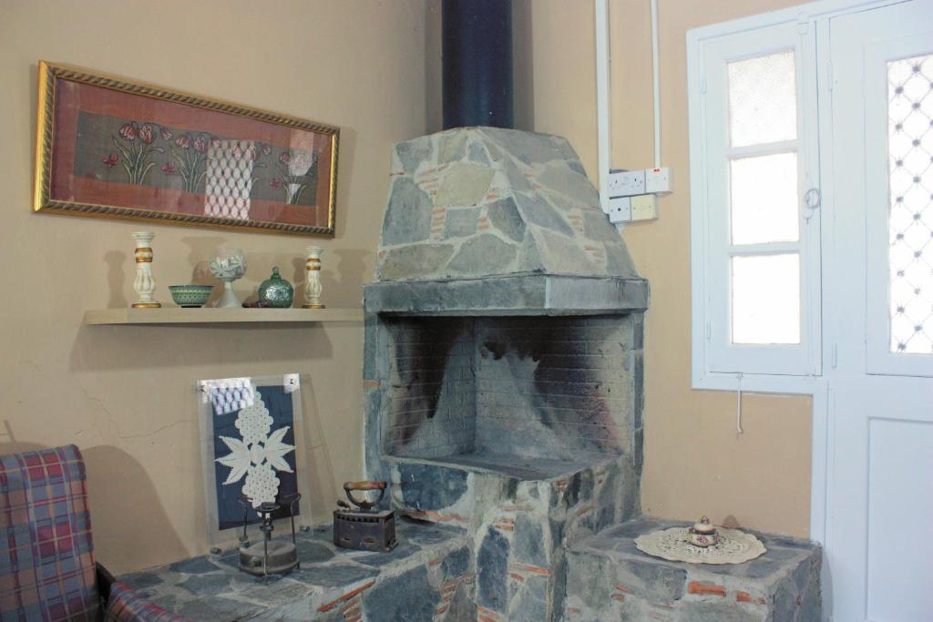 una chimenea de piedra en la esquina de una habitación en Laoni Guest House in Moutoullas, Marathasa, en Limassol