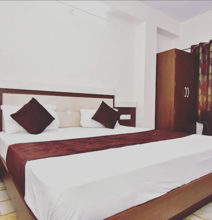 a bedroom with a large white bed with black pillows at Hotel Vaidehi in Udaipur