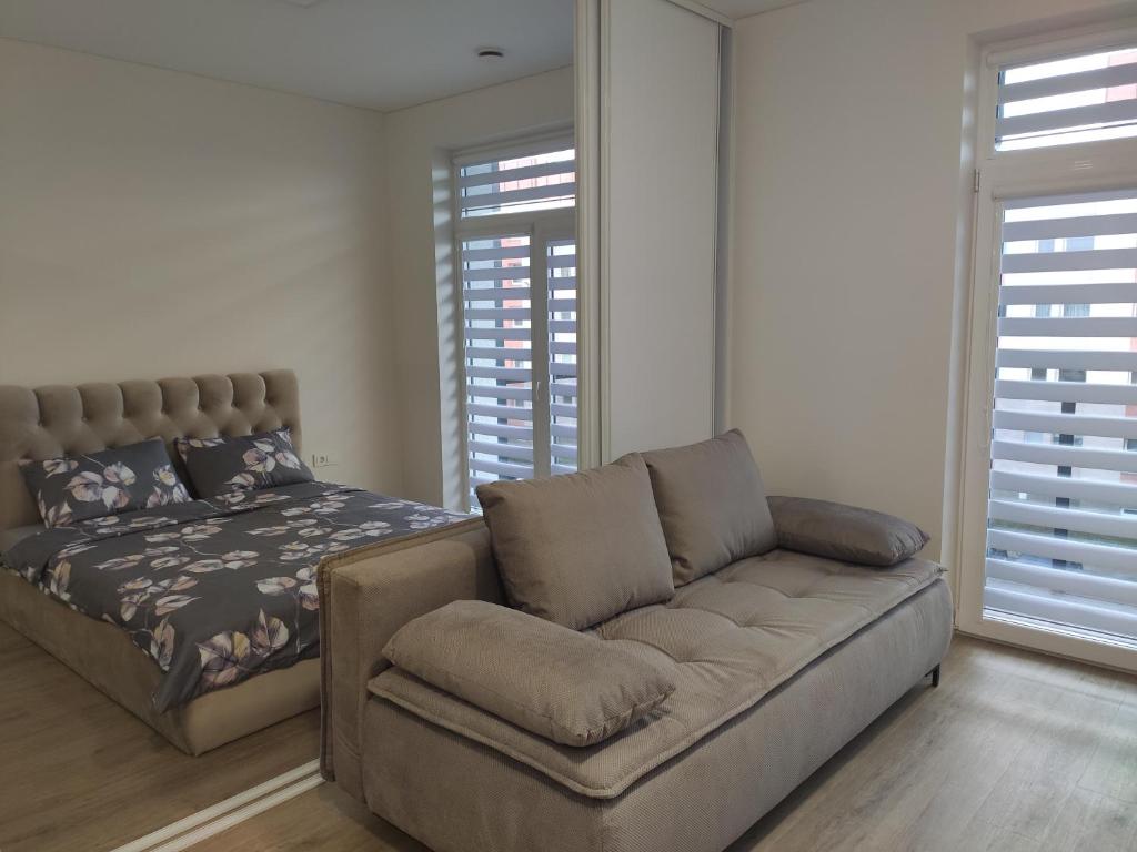 uma sala de estar com um sofá e uma cama em Apartment Ainiai em Panevėžys