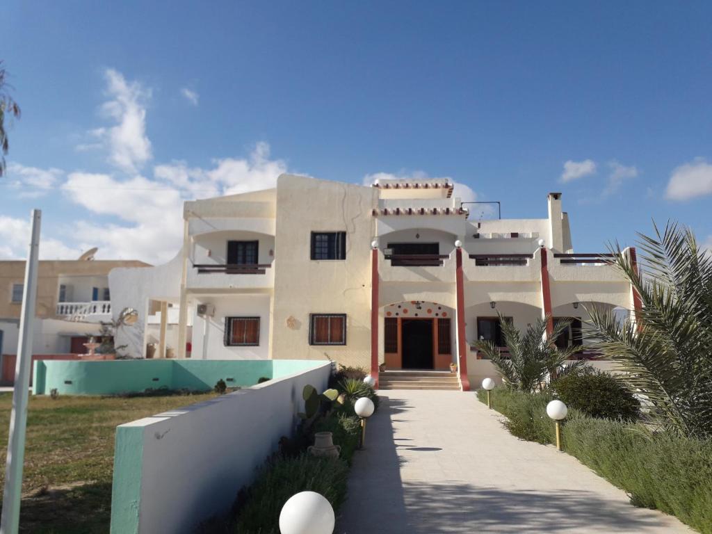 ein weißes Haus mit einem Gehweg davor in der Unterkunft Appart Gyptis Résidence Chahrazad in Sfax