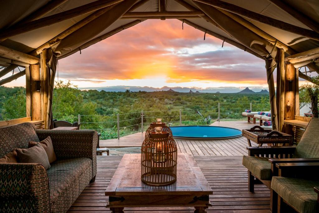 a screened in porch with a table and a sunset at Bundox Explorer Camp in Hoedspruit