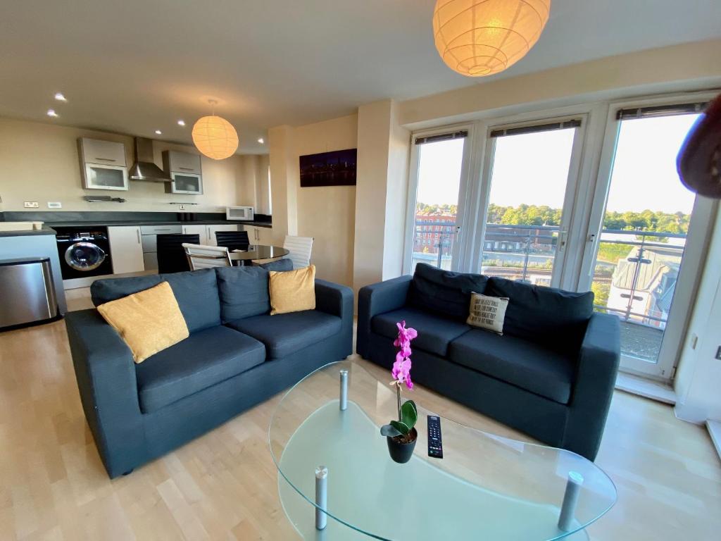 a living room with a blue couch and a glass table at Basingstoke Central Apartments in Basingstoke