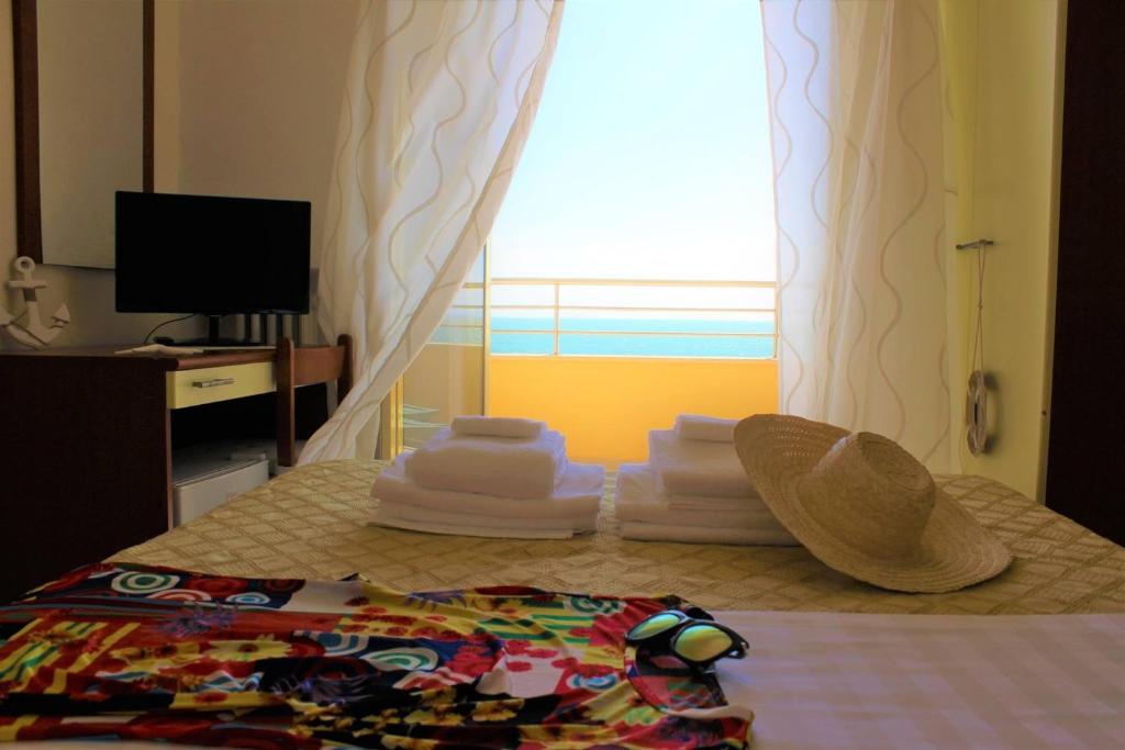 - une chambre avec un lit avec un chapeau et des serviettes dans l'établissement Hotel Panoramico, à Scauri