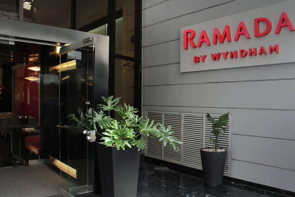 a entrance to a restaurant with potted plants in front of the door at Ramada by Wyndham Buenos Aires Centro in Buenos Aires