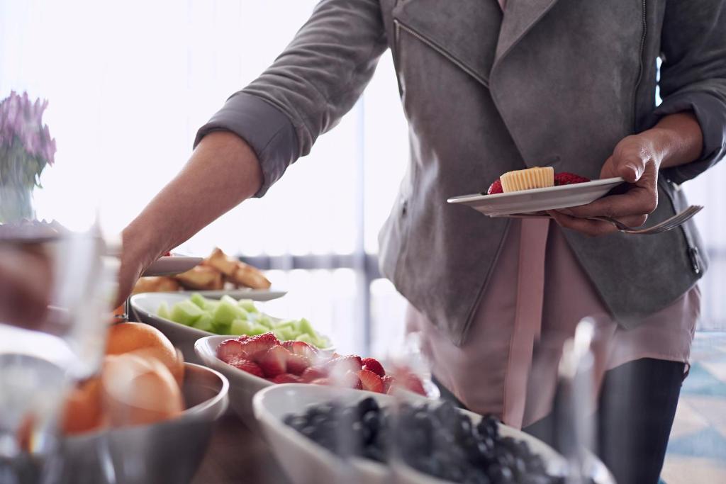 a person holding a plate of food with fruits and vegetables at Crowne Plaza Bahrain by IHG in Manama