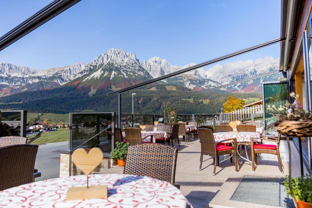 a balcony with tables and chairs with mountains in the background at Café-Restaurant Bettina in Ellmau