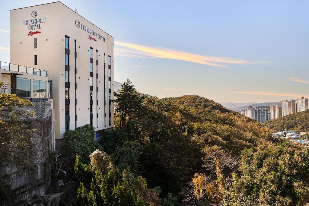 釜山にあるBrown Dot Hotel Signatureの木立の丘の上の建物