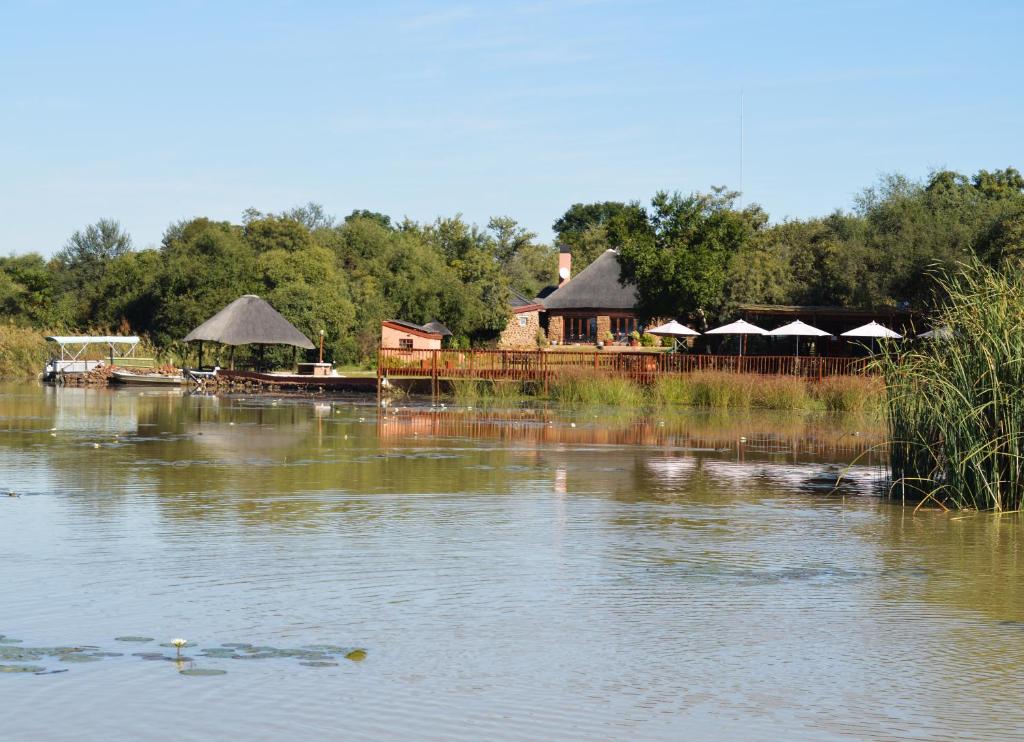 einem großen See mit einer Gruppe von Gebäuden und Bäumen in der Unterkunft Crocodile Pools Resort in Gaborone