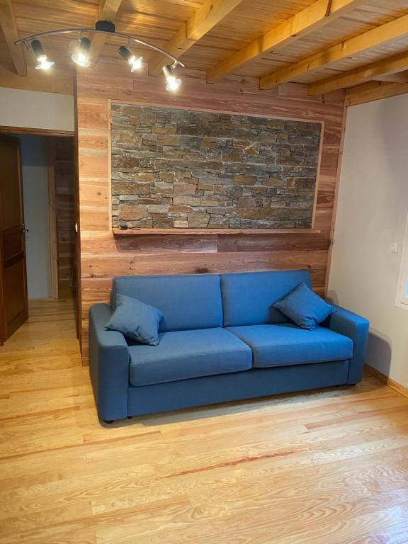 Sofá azul en una habitación con pared de ladrillo en Appartement rénové 4pers tout confort & garage, en Cauterets