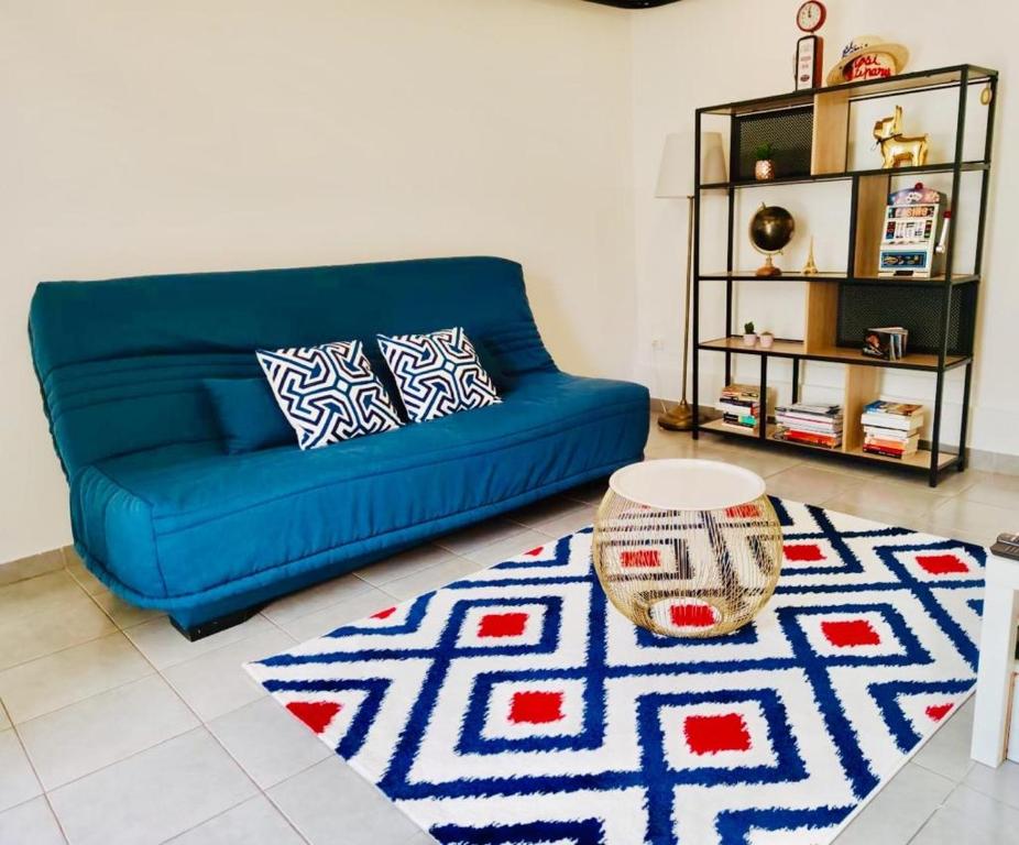 een blauwe bank in een woonkamer met een tapijt bij STUDIO COSY LE Ti PARIS WIFI & NETFLIX in Deuil-la-Barre