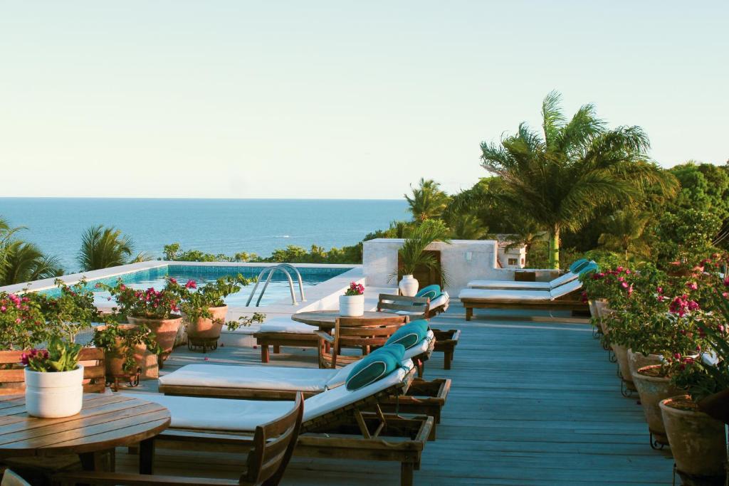 a patio with tables and chairs and the ocean at Hotel Maitei in Arraial d'Ajuda