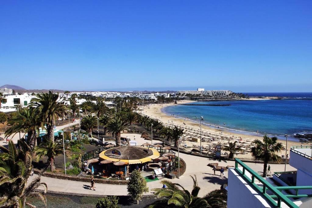 een uitzicht op een strand met palmbomen en de oceaan bij Design Vivienda V El Burgao by the Sea in Costa Teguise