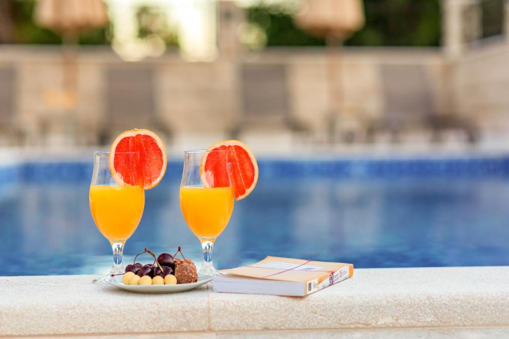 two glasses of orange juice and a plate of fruit at Luxury Apartments Queen in Petrovac na Moru