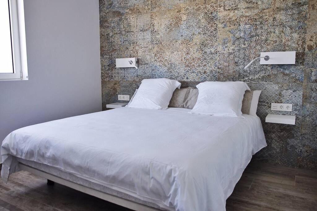 sypialnia z białym łóżkiem z ceglaną ścianą w obiekcie Design Vivienda V El Burgao by the Sea w Costa Teguise