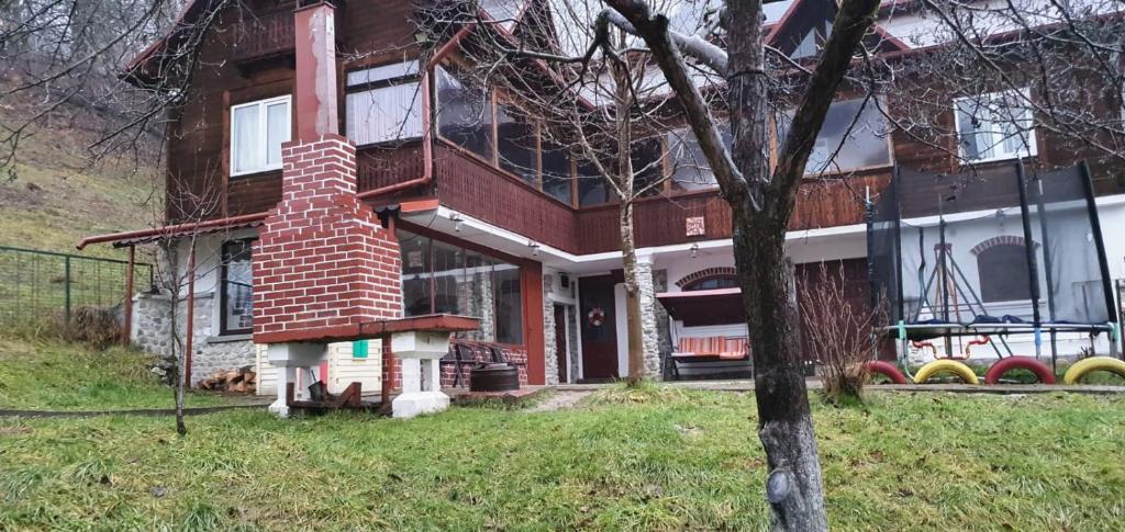 a house with a brick chimney on the front of it at Casa COLT DE RAI in Brezoi