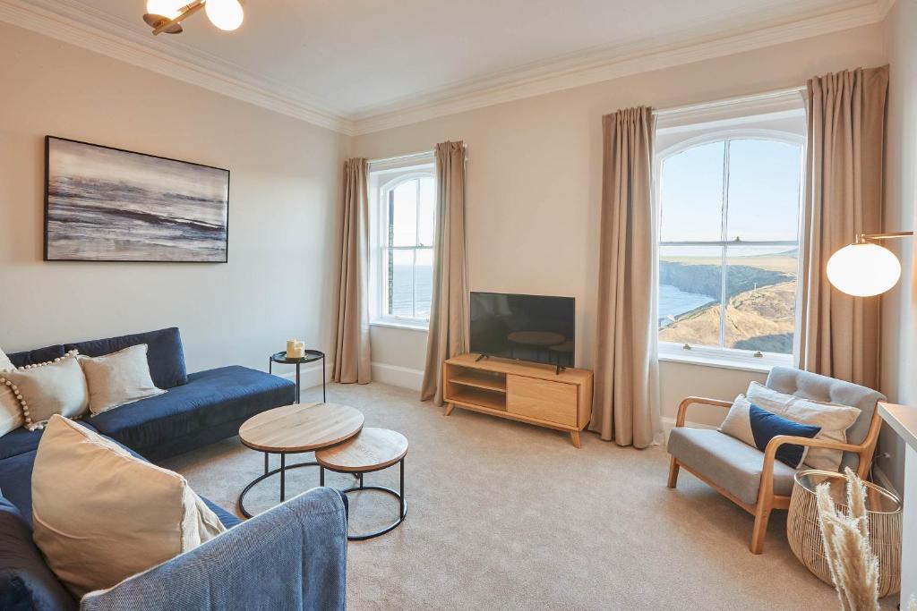 a living room with a blue couch and a tv at Host & Stay - Huntcliff View Apartment in Saltburn-by-the-Sea