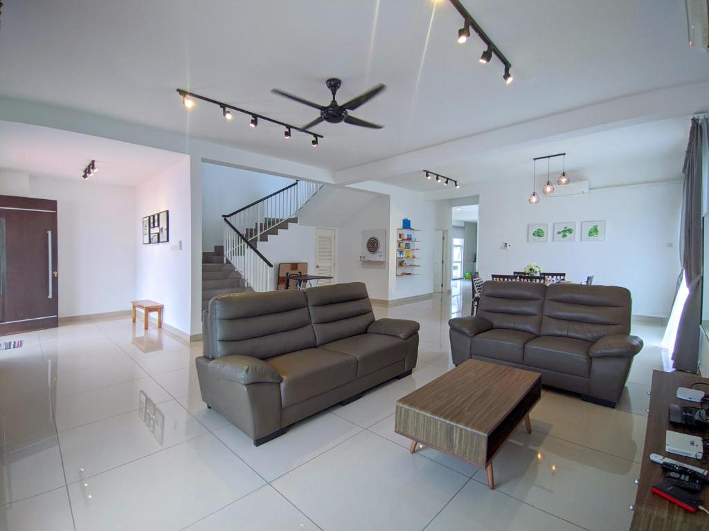 una sala de estar con 2 sofás de cuero y una mesa. en Hom Villa 5rm 12-22 pax Wifi Netflix BBQ SteamBoat Games Beach Water Park, en Kota Tinggi